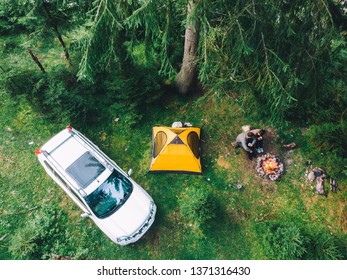 couple sitting near campfire drinking tea. yellow tent and white suv car. active leisure time - Powered by Shutterstock