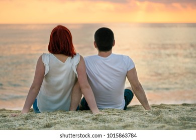 
Couple sitting on beach. Man woman watching sunset. Relations travel lifestyle concept.