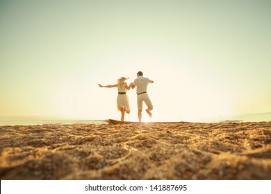 Couple Sitting On The Beach At Sunrise