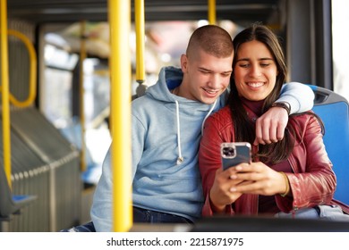 Couple Sitting On A Bus Seat, Looking At A Phone, Hugging And Having Good Times Browsing The Internet While Commuting