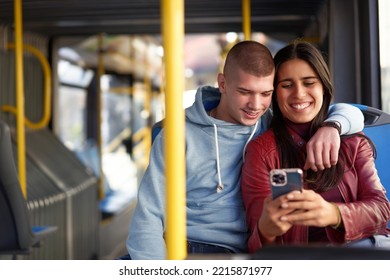 Couple Sitting On A Bus Seat, Looking At A Phone, Hugging And Having Good Times Browsing The Internet While Commuting