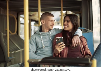 Couple Sitting On A Bus Seat, Looking At A Phone, Hugging And Having Good Times Browsing The Internet While Commuting