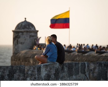 Couple sitting on city wall with colombian national flag waving in wind on Bastion of Santo Domingo Cartagena Colombia - Shutterstock ID 1886325739