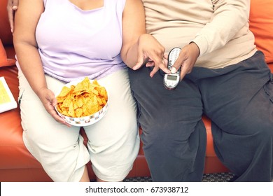 Couple Sitting On Couch With Crisps And Phone, Mid Section