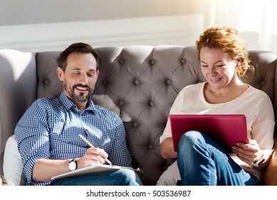 Couple Sitting On Couch With Laptop And Notes