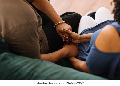 Couple Sitting On Couch Praying Together