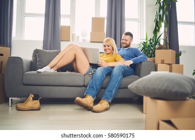 Couple Sitting On The Couch And Searching Internet On Laptop