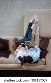 Couple Sitting On Couch With Their Dog