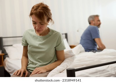 Couple sitting on different sides of bed not talking after argument - Shutterstock ID 2318949141