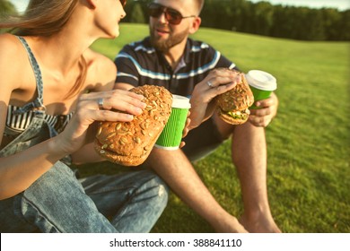 couple sitting on the grass in the park and eating sandwiches smiling
 - Powered by Shutterstock