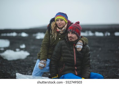 Couple Sitting On Ice Block At Black Beach