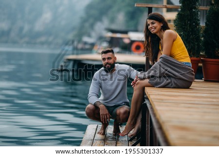 Couple sitting on lake pier and sharing some relaxing moments.