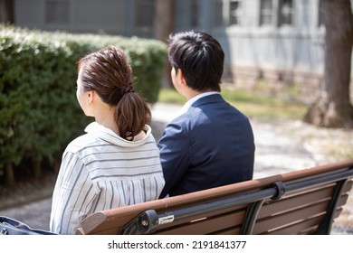 A Couple Sitting On A Park Bench Saying Goodbye