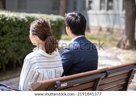 A couple sitting on a park bench saying goodbye
