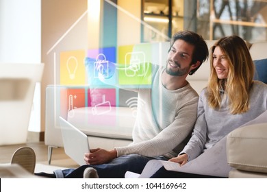 A couple sitting on the sofa controls all the functions of the house such as wi-fi, heating, lighting, television through holography. Concept of, home automation, automations, future, technology.