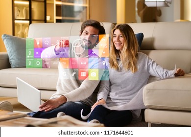 A couple sitting on the sofa controls all the functions of the house such as wi-fi, heating, lighting, television through holography. Concept of, home automation, automations, future, technology. - Powered by Shutterstock