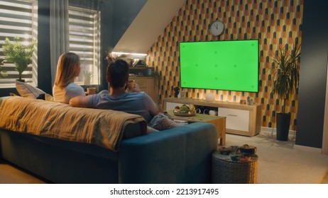 Couple sitting on sofa in living room, talking, watching breaking news, movie or series on TV. Wife and husband resting and chilling at home in the evening together. Green screen. Chromakey. - Powered by Shutterstock