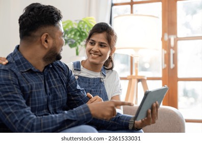 a couple sitting on the sofa in the living room Surf the internet on your tablet and chat in relaxing time. - Shutterstock ID 2361533031