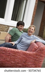 Couple Sitting On Sofa Outside House