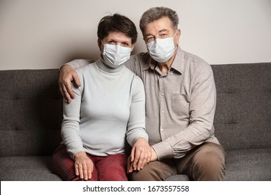 A couple sitting on a sofa wearing a protective mask. An infectious agent protection gear  including a mask. An sick older man and woman wearing protective masks to protect against virus. Coronavirus. - Powered by Shutterstock