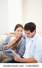 Couple sitting on a sofa while reading a newspaper in a sitting room