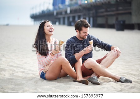 couple sitting in sand at santa monica pier.