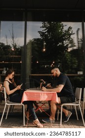 Couple sitting and talking, hold electronic gadgets and share information in cafe. Colleagues concentrated on project ignoring communication using devices. Freelancing and networking concept. - Shutterstock ID 2364785117