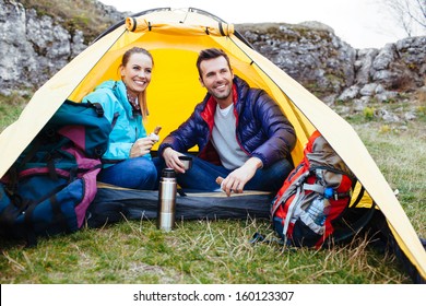 Couple Sitting In A Tent. Camping Near The Rocks