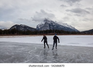 Couple Skating On A Frozen Lake. Picture Taken In Banff, Alberta, Canada.