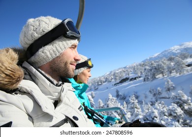 Couple Of Skiers Going Up Ski Slope With Chairlift