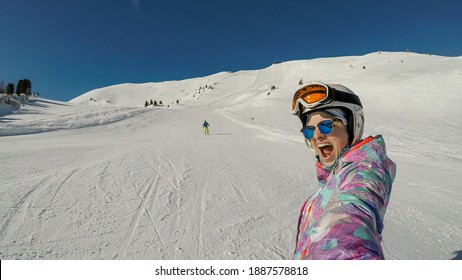 Couple in skiing outfit sliding down the ski run of Innerkrems, Austria. The woman is taking a selfie. Perfectly groomed slopes. Cloudless sky. Having fun. Winter outdoor activity. Massive ski resort - Powered by Shutterstock