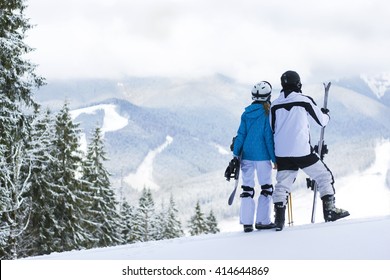 Couple Skiing And Snowboarding Outside In The Mountains