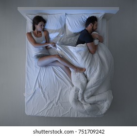 Couple Sleeping In Bed, The Man Is Stealing The Duvet And The Woman Is Angry And Freezing