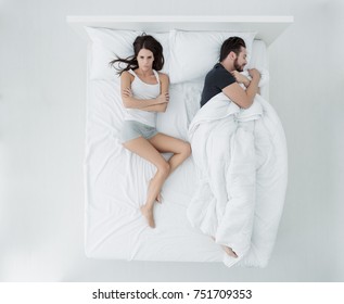 Couple Sleeping In Bed, The Man Is Stealing The Duvet And The Woman Is Angry And Freezing