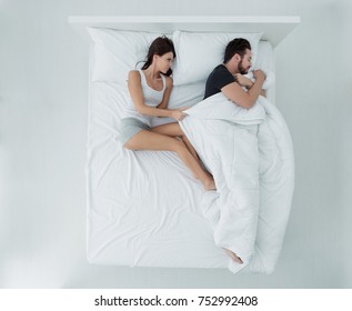 Couple Sleeping In Bed, The Man Is Stealing The Duvet And The Woman Is Angry And Freezing