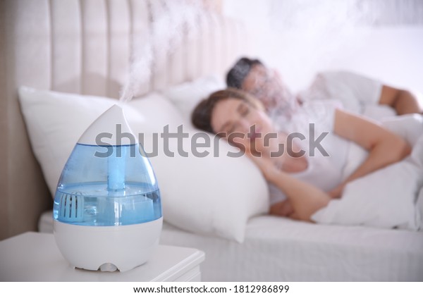 Couple\
sleeping in bedroom with modern air\
humidifier