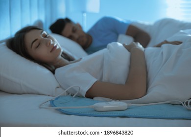 Couple Sleeping On Electric Heating Pad In Bed At Night