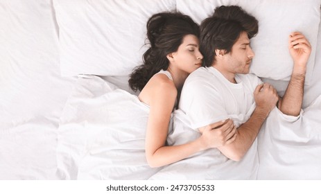 A couple is sleeping peacefully in bed together, with the woman nestled against the mans back, wearing white shirts and are completely relaxed, suggesting a comfortable and loving relationship. - Powered by Shutterstock