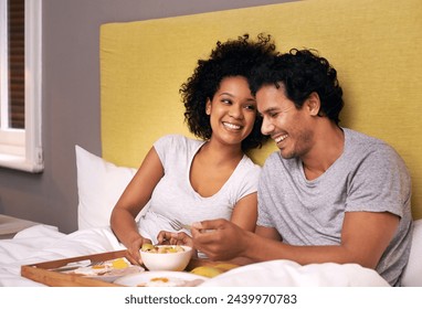 Couple, smile and bedroom for breakfast on tray for wakeup, morning and food for eat, rest and relax. Diverse and young people and laugh with happiness for bonding with fruit and bowl for joy - Powered by Shutterstock