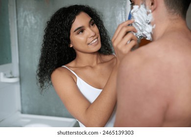 Couple, smile and shaving face in bathroom for health, hygiene or wellness together in home. Cream, man and woman with razor on beard for beauty, help and grooming for hair removal on morning routine - Powered by Shutterstock