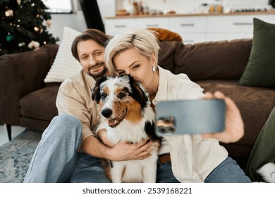 A couple smiles joyfully while taking a selfie with their playful dog in a cozy living room.