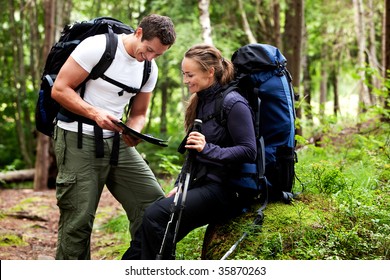 A couple with smiles looking at a map in the forest - Powered by Shutterstock