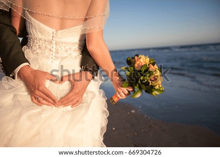 Couple smiling and embracing near wedding arch on beach. Honeymoon on sea or ocean