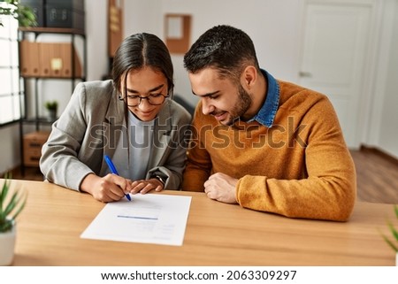 Couple smiling happy reading document at the office.