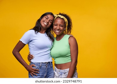 Couple smiling Indian and African American girl pose hugging looking cheerful to camera isolated on yellow color background. Homosexual relationship of happy lesbian girlfriends in positive attitude. - Powered by Shutterstock