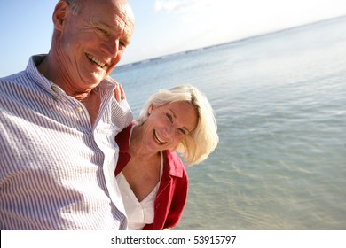 Couple of smiling seniors having a walk by the edge of the sea - Powered by Shutterstock