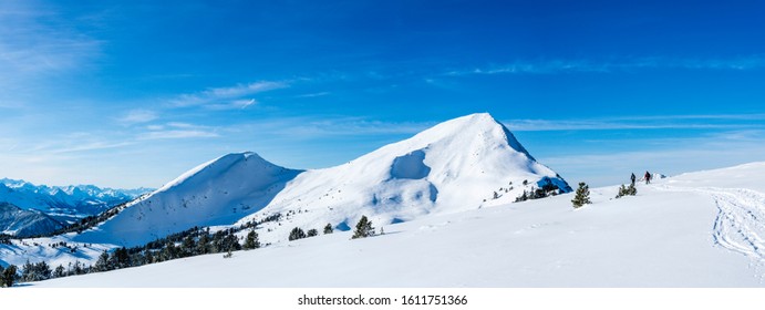 Couple Snow Shoeing / Ski Touring In The Snow Covered Winter Landscape. Health Concept, Couple Activities. Sunny Day Blue Sky