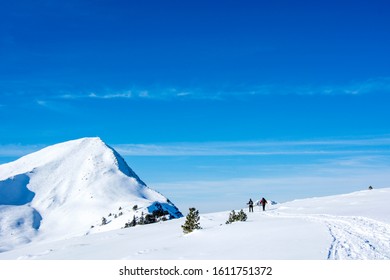 Couple Snow Shoeing / Ski Touring In The Snow Covered Winter Landscape. Health Concept, Couple Activities. Sunny Day Blue Sky