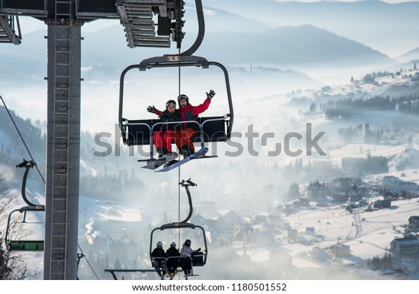 Couple snowboarders having fun on a ski lift in\
ski resort with beautiful background of snow-covered slopes,\
forests, hills copyspace recreation travelling tourism vacation\
mountains Bukovel,\
Ukraine