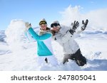 Couple in snowy mountain doing snowballs fight